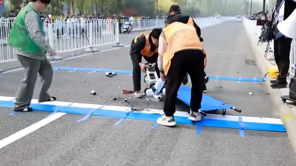 工作人員到場將機械人抬上擔架，並將散落在地上的零件也一併拾起，之後迅速離場。（網上影片截圖）