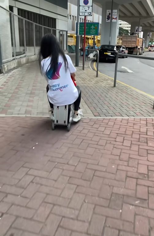 女子帶小孩騎電動行李箱周街走