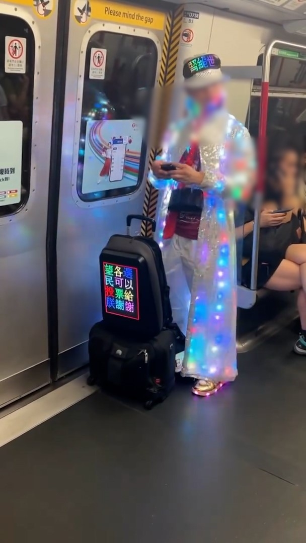 在港鐵車廂內，一名戴眼鏡男子身穿銀色長褸，身上滿布彩色燈光，不停閃爍。（Threads影片截圖／sonaroy2860）