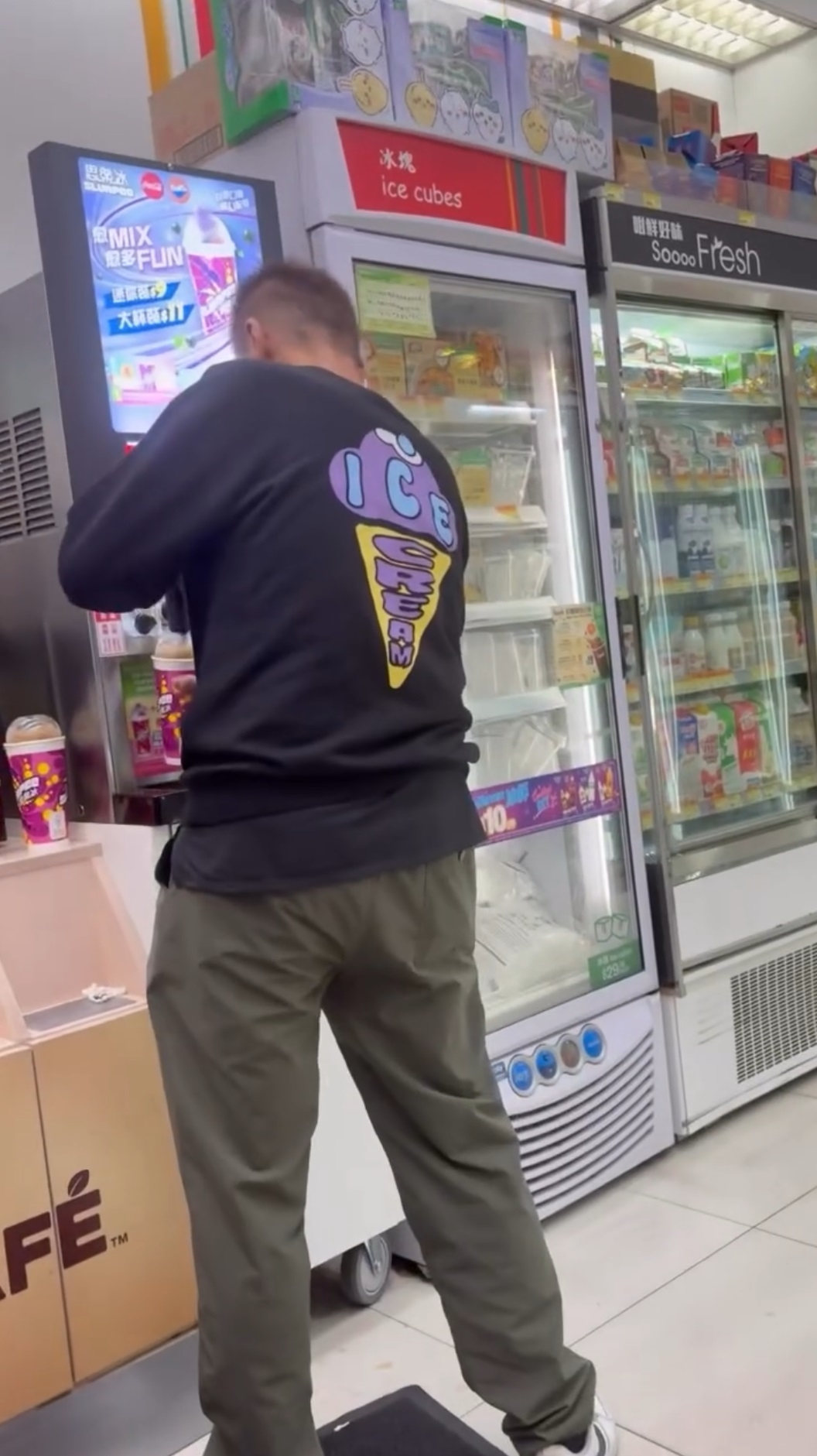 一名身穿深色長袖上衣綠色長褲的男子，在便利店內背對鏡頭，在店內的飲料機裝取飲品。（Threads影片截圖／yoyoyo_ching）