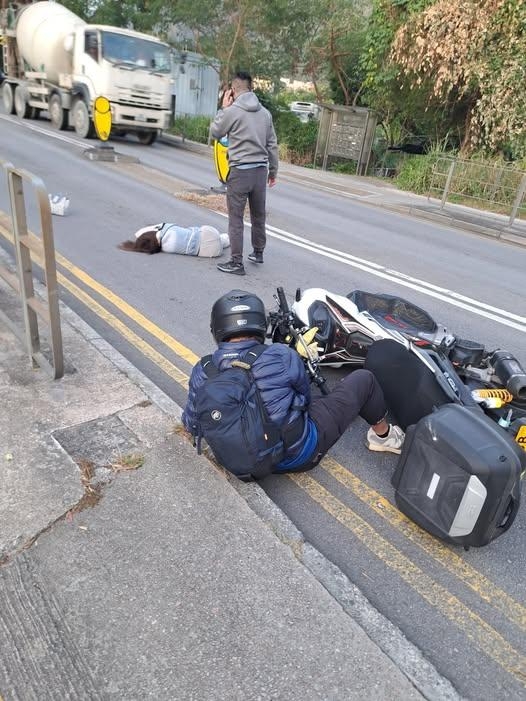 大埔今日（25日）早上發生交通意外。一名58歲婦人在坪朗路近公廁對開過路時，遭一輛電單車撞倒，婦人應聲倒地，身體橫躺在行車線上，電單車亦翻側，騎士坐在地上。（FACEBOOK圖片）
