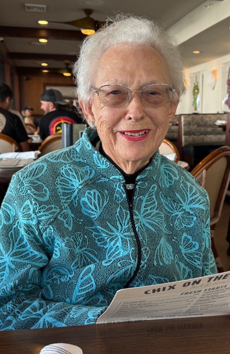 Ruth Lemay in a blue jacket smiling at a restaurant table.