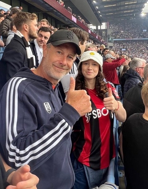 A man and a woman in a stadium crowd giving thumbs up.