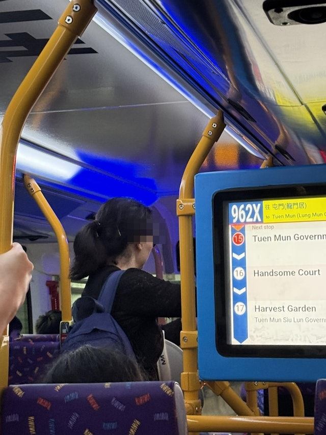 相片中，戴着「黑超」、穿黑衣的大媽走到巴士車廂上層，但未有坐下。