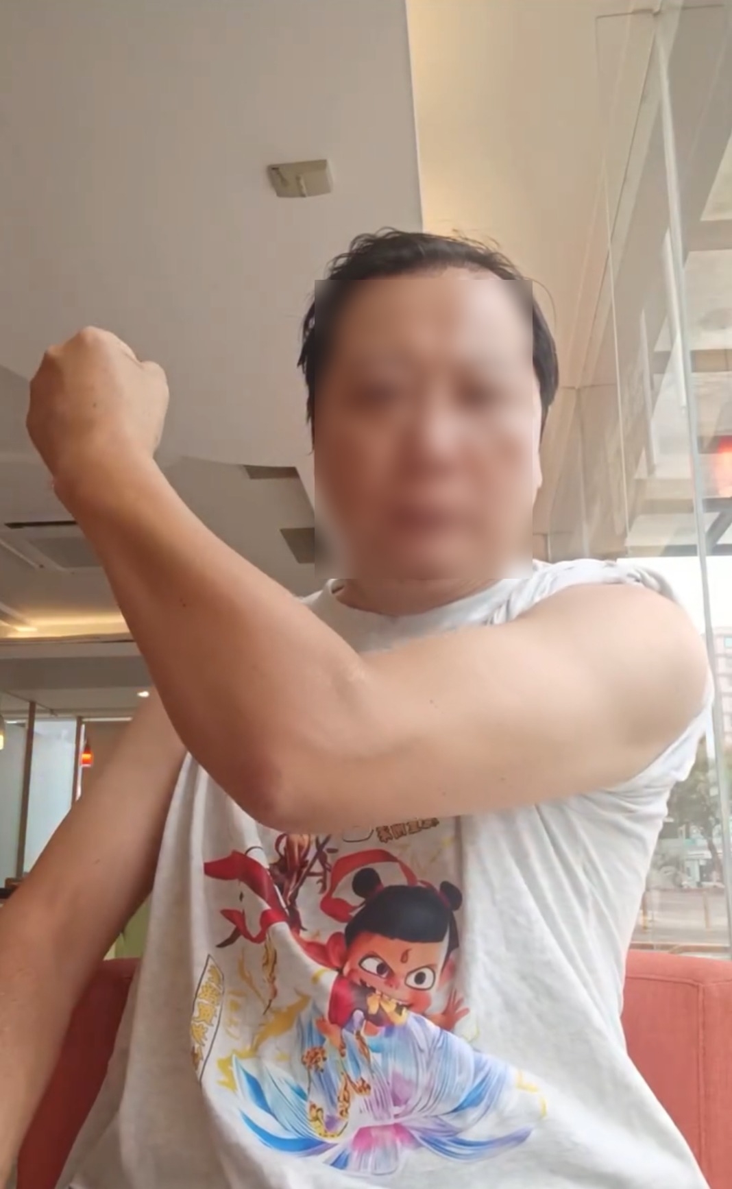 影片中，該名男士身穿哪吒公仔上衣，坐在鏡頭前展示肌肉及連續出拳，揮動拳頭時氣勢十足，彷彿空氣都被劈開。