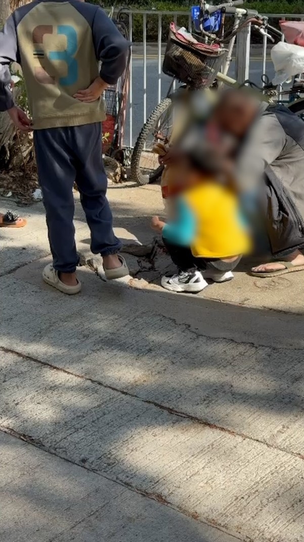 涉事小朋友和男性長輩一同蹲在街上吸煙，較年長的小朋友則站在旁邊。（報料觀眾提供影片截圖）