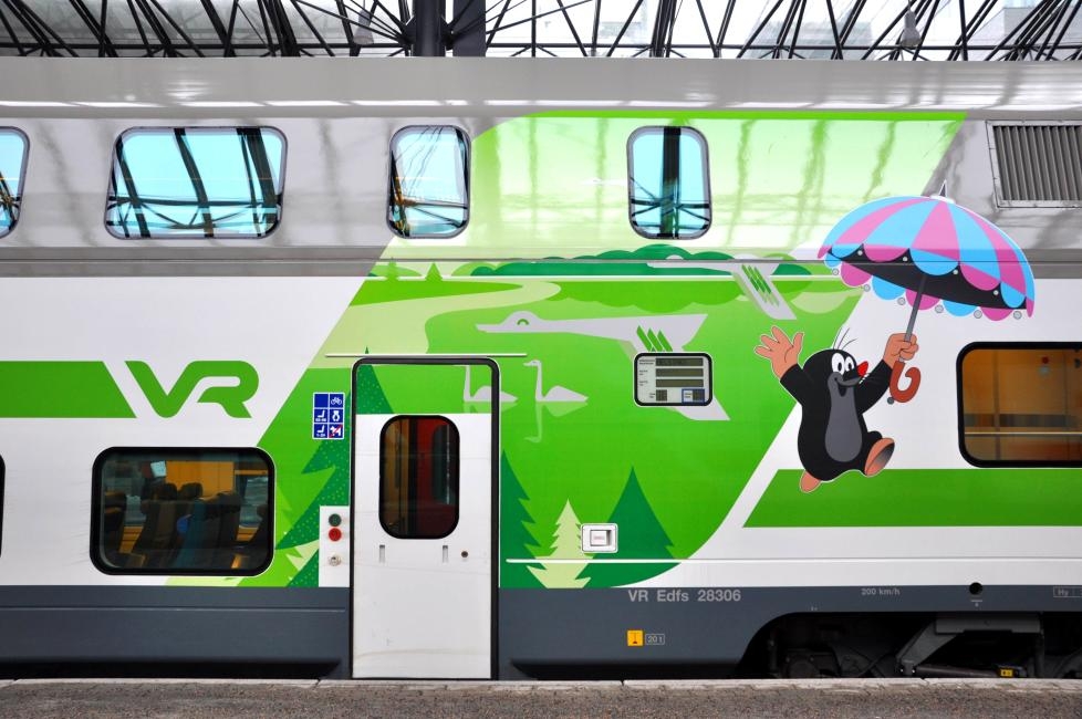 芬蘭VR火車車廂外觀，繪有可愛的姆明谷卡通人物提著雨傘在綠色風景中飛翔，為旅程增添童趣。